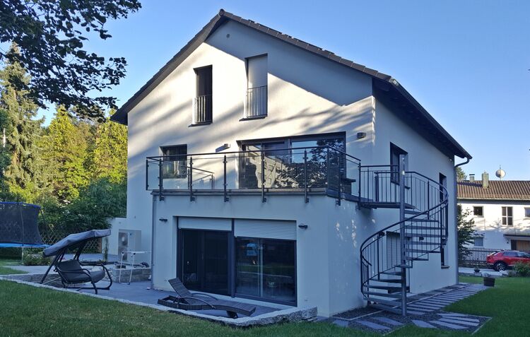 Zweifamilienhaus bauen in München –  Rückansicht des Zweifamilienhauses mit Terrasse und Wendeltreppe.