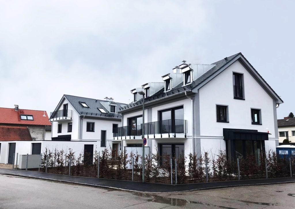 Doppelhaus bauen – Doppelhaus mit weißer Fassade und Garage.