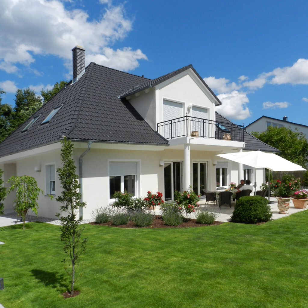 Dachformen fürs Haus – Ein Haus mit weißer Fassade, Walmdach und umliegendem Garten.