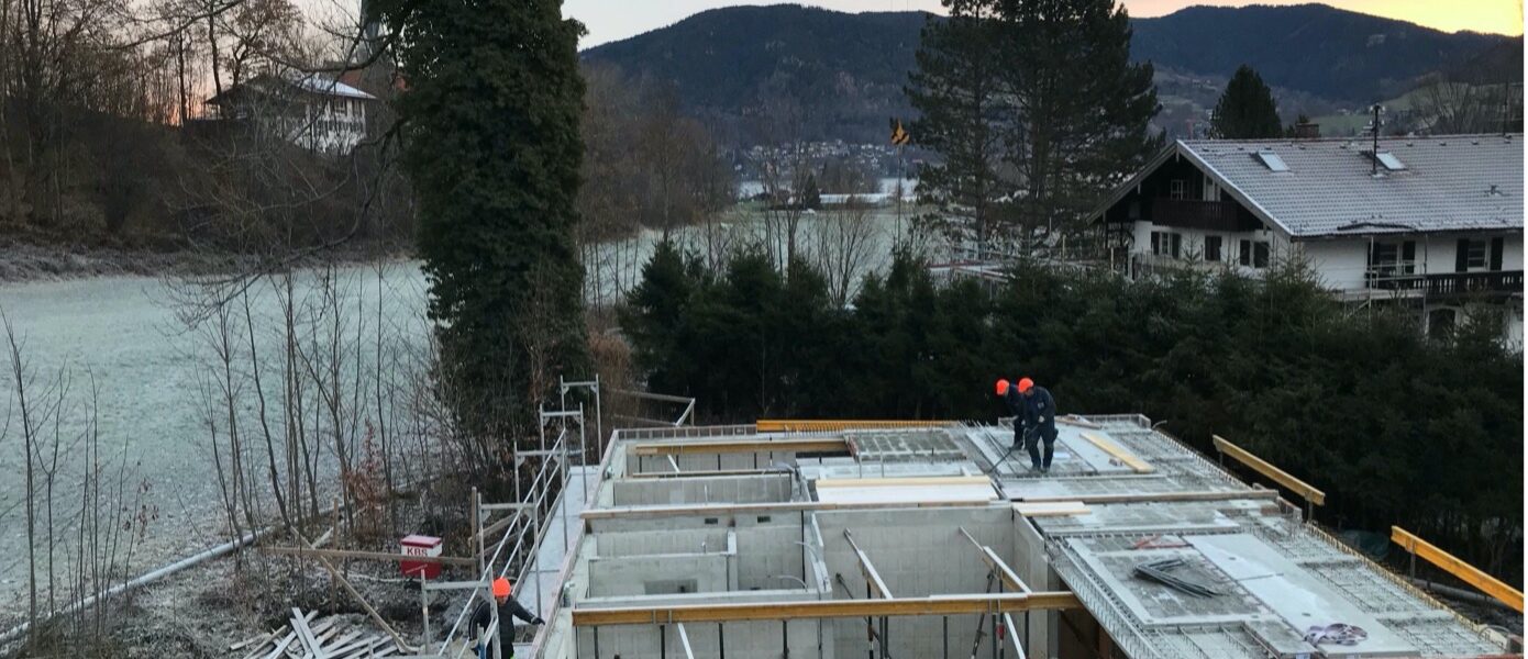Hausbau im Winter – Arbeiter stehen auf der mit Reif bedeckten Baustelle eines Rötzer Ziegel-Element Hauses.
