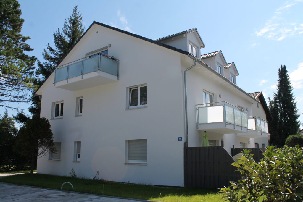 Mehrfamilienhaus als Kapitalanlage – Ein Mehrfamilienhaus von Rötzer mit weißer Fassade in der Rückansicht.