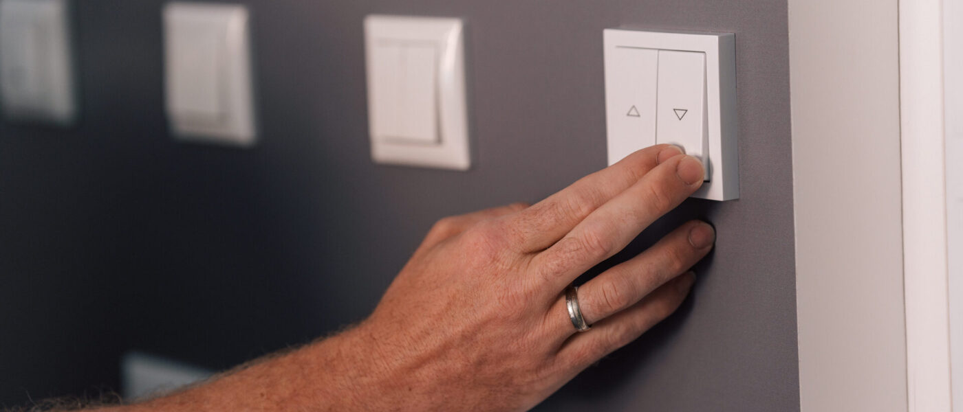 Smart Home Möglichkeiten – eine männliche Hand betätigt einen Schalter an der Wand.