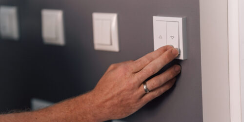 Smart Home Möglichkeiten – eine männliche Hand betätigt einen Schalter an der Wand.