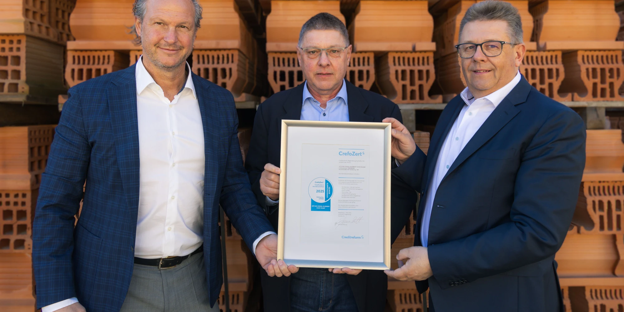 Drei Menschen halten eine Urkunde