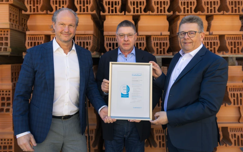 Drei Menschen halten eine Urkunde